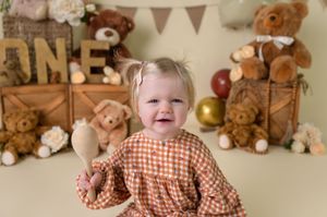 A cozy nursery scene with teddy bears and plush toys arranged around rustic wooden crates and bunting decorations.