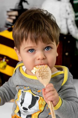 Young child in gray sweatshirt eating a cookie while wearing a yellow bib with animal design.