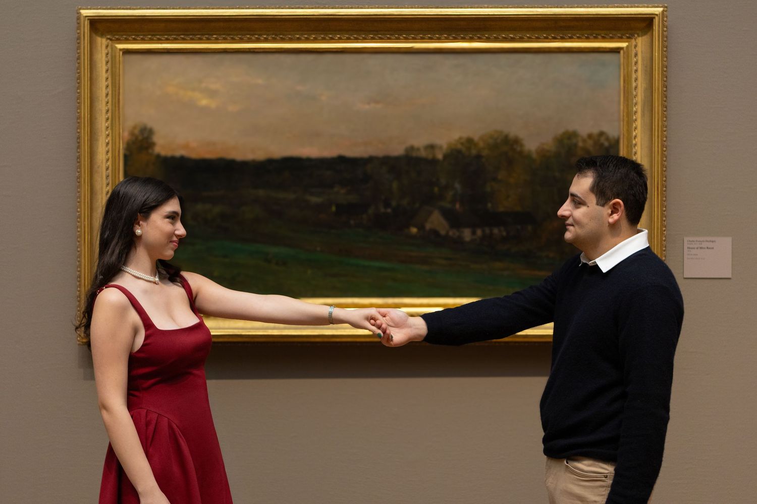 Two dancers in formal attire perform an elegant ballroom dance routine on a wooden floor.