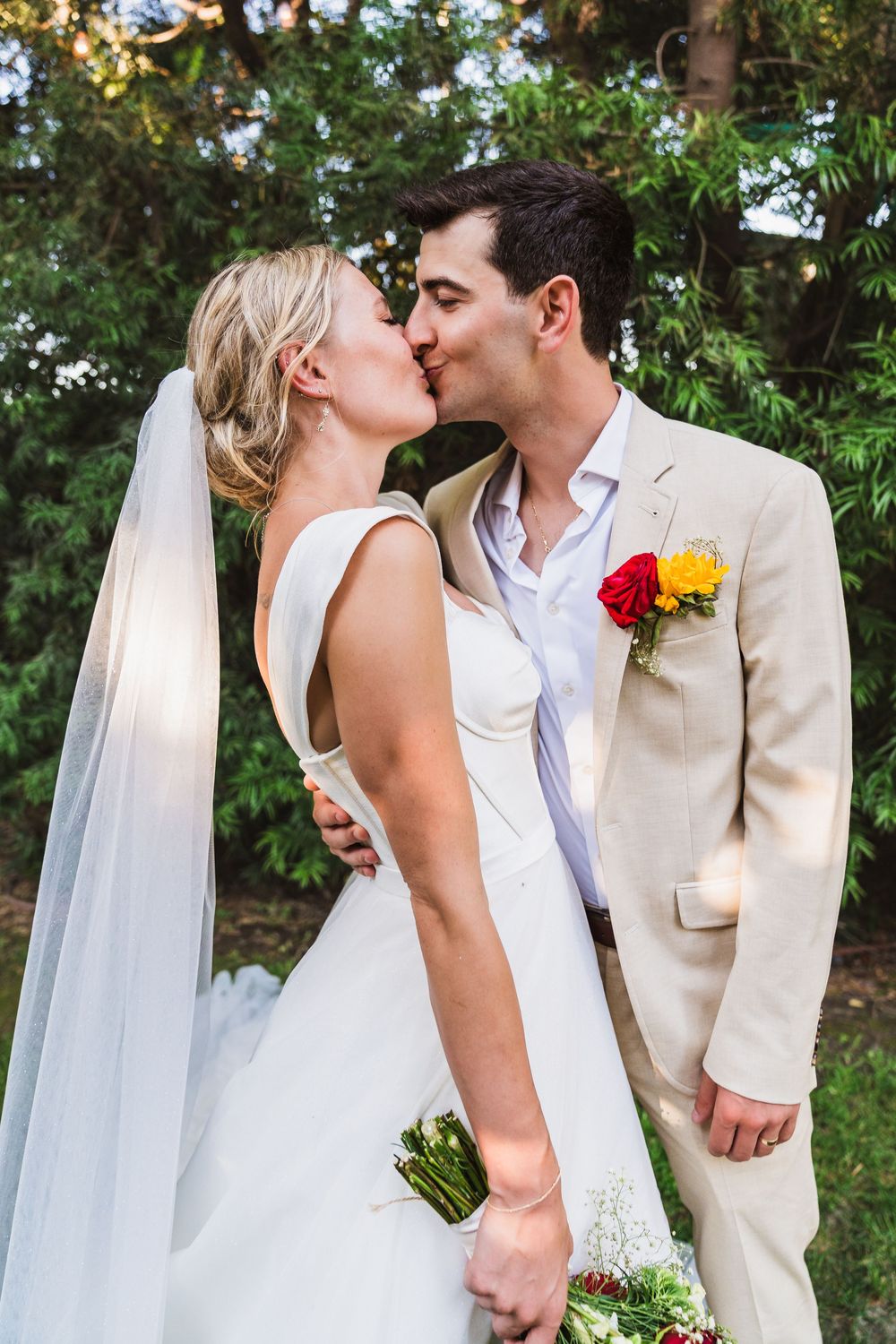 A couple shares romantic moments in a garden setting on their wedding day.