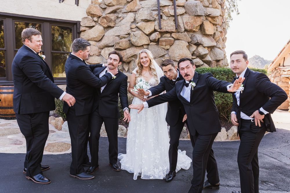 Wedding party poses playfully with groomsmen striking dramatic poses around the newlyweds.