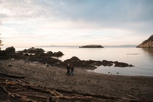 Scenic panoramic view of a rocky coastline with calm waters and distant islands during sunset.