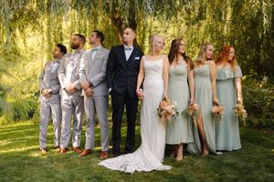 Wedding party poses under a weeping willow tree during golden hour creating a romantic outdoor setting.