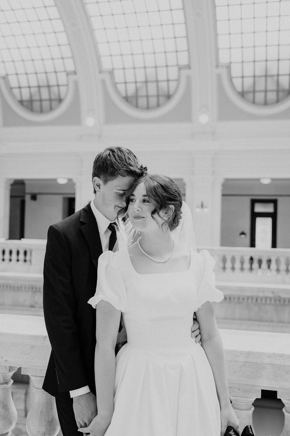 Black and white photo of bride and groom sharing an intimate moment in elegant marble venue.