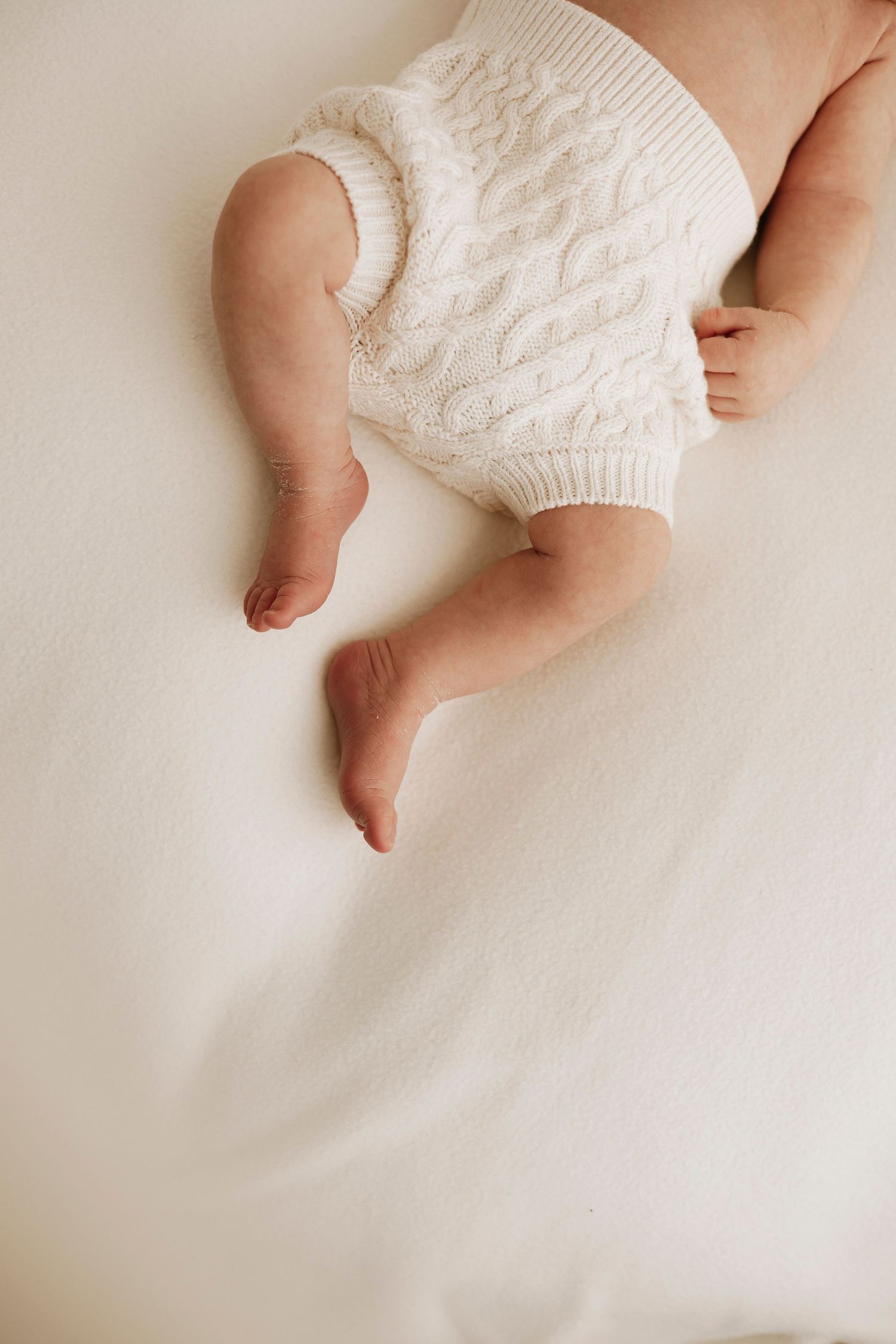 newborn feet with neutral knitted shorts on a white newborn beanbag - newborn photographer