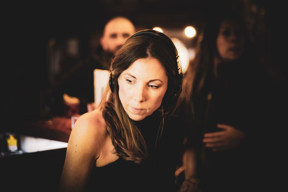 A person with dark hair sits in dramatic lighting with a soft glow illuminating their profile.