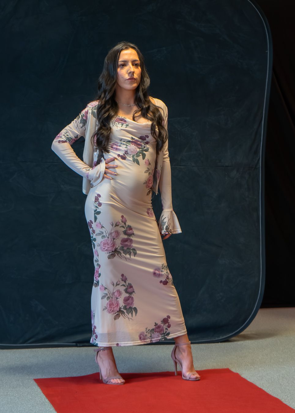 Model poses in a light pink floral dress against dark backdrop showing different angles of the flowing garment.