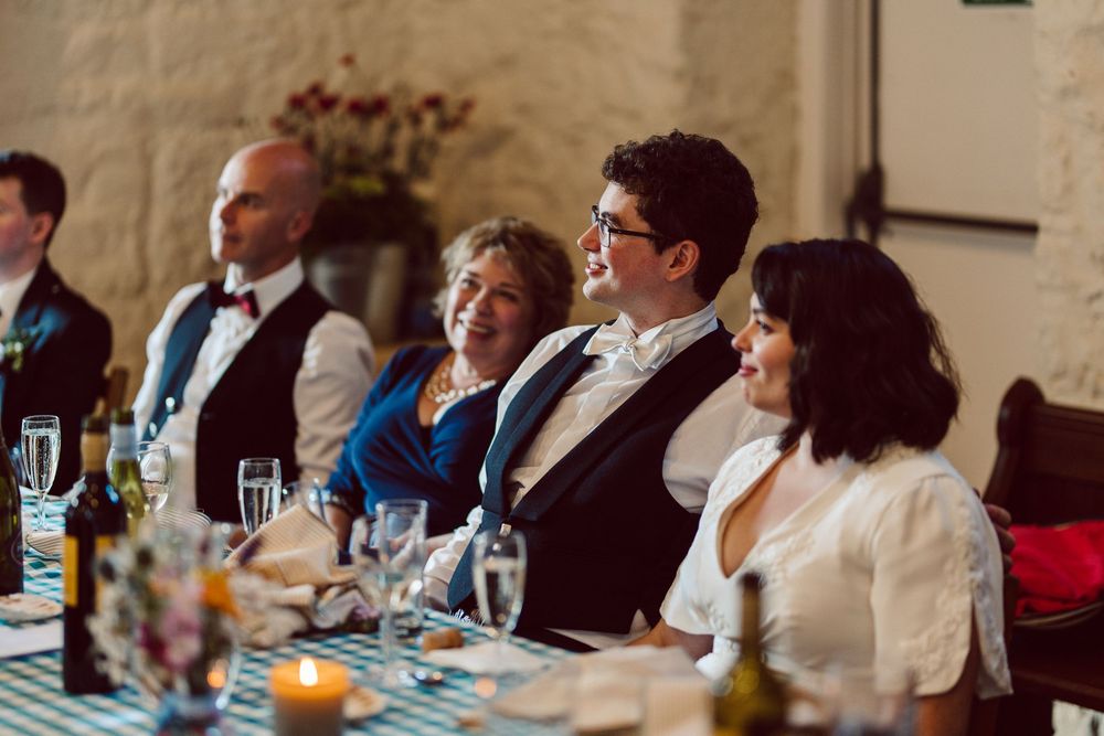 A group of people seated at a long dining table in a formal setting with glassware and table settings.