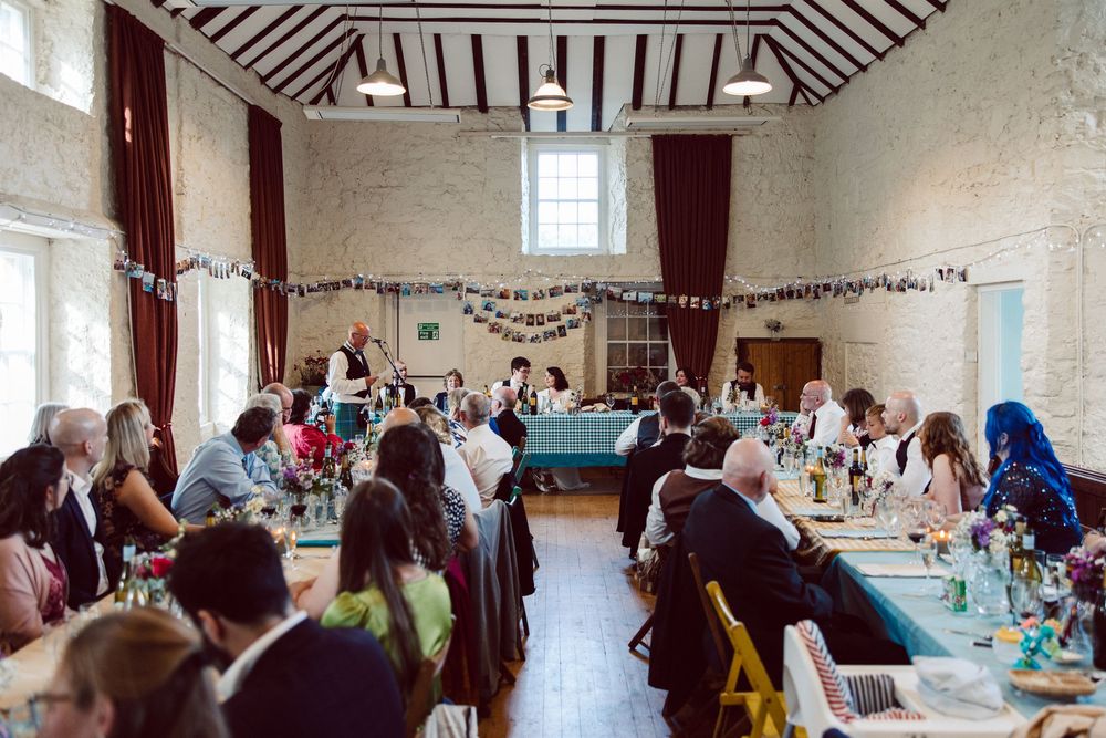 A panoramic view of a large reception hall decorated with tables and chairs for a wedding celebration.