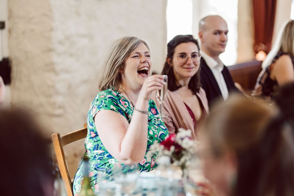 Wedding guests share a joyful moment of laughter during a reception celebration.