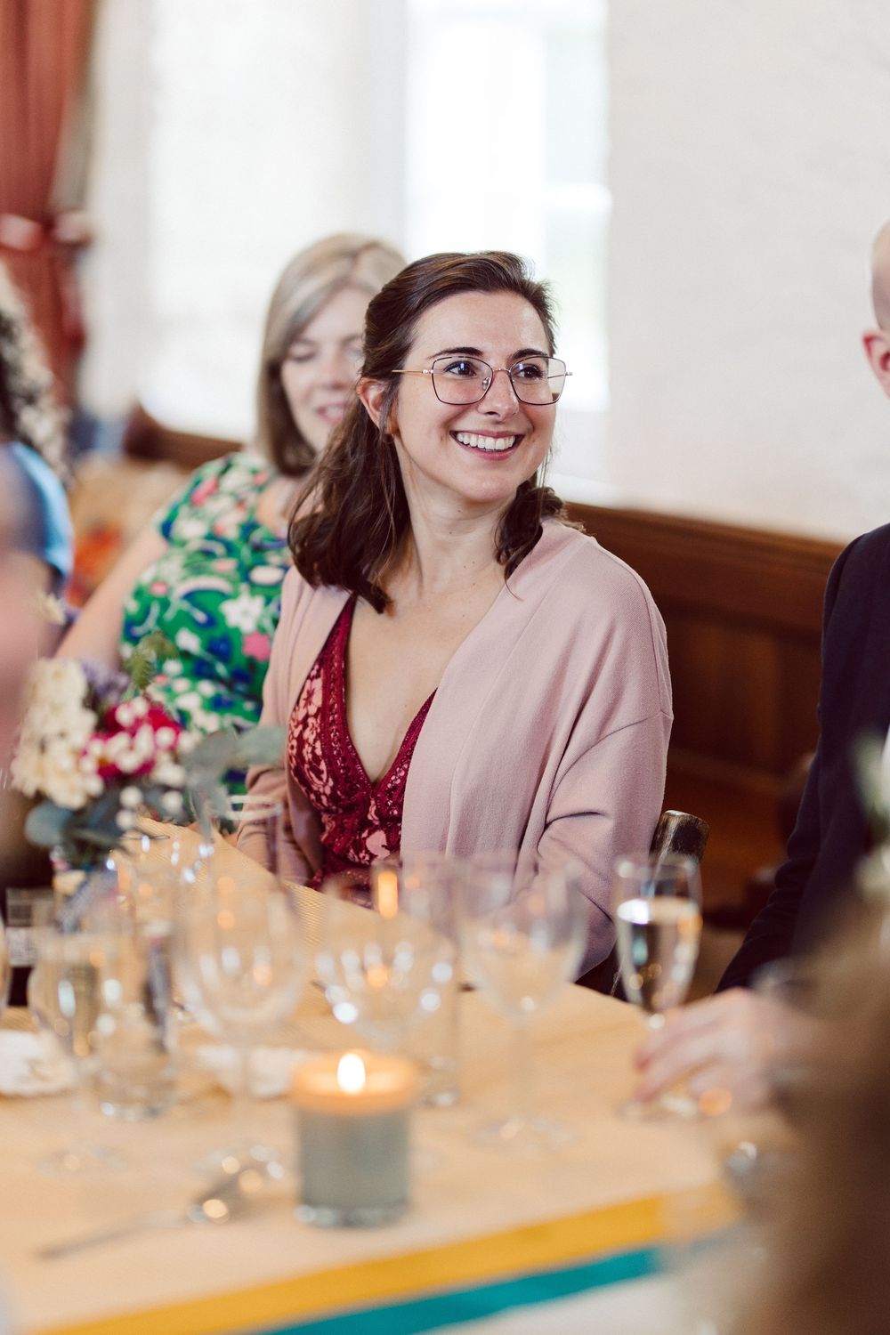 A sequence of candid dinner party photos showing a guest in a pink blazer smiling at a decorated table setting.