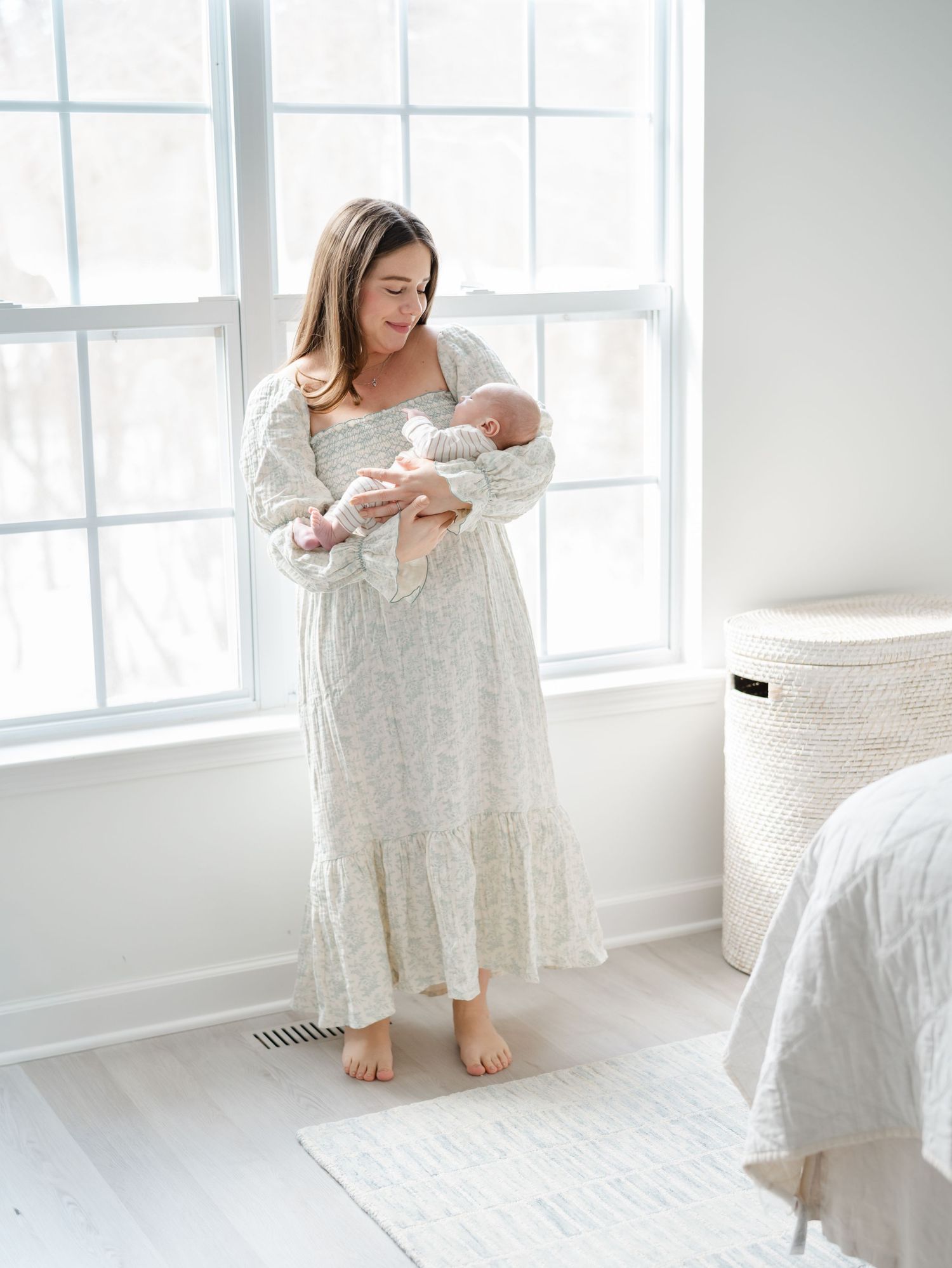 Mother holding newborn in softly lit bedroom during in-home newborn session in Monmouth County NJ.