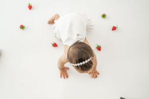 Small red strawberries scattered on a white surface create a minimalist food photography composition.