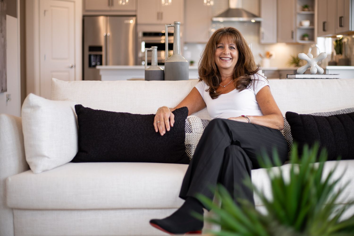 A realtor smiling on a white couch in a modern living room with black accent pillows in Boyds MD during a personal branding session.