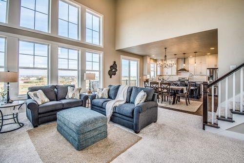 An open concept living room with large windows, plush furniture, and natural light streaming in.
