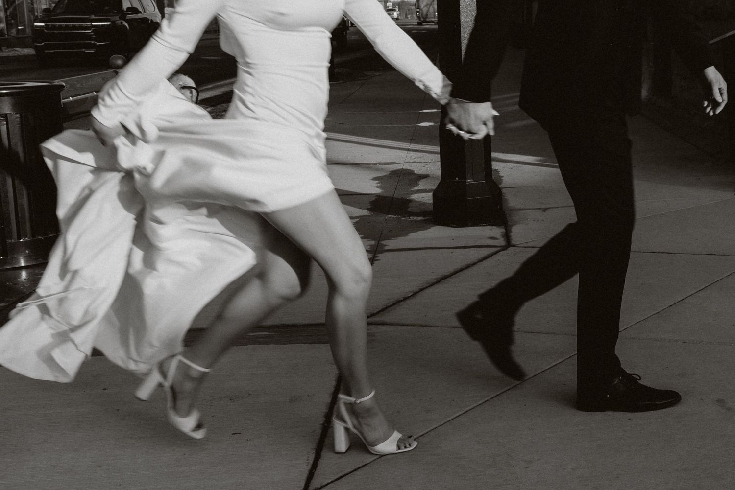 Black and white image a couple running across the street during their luxury elopement session in alberta