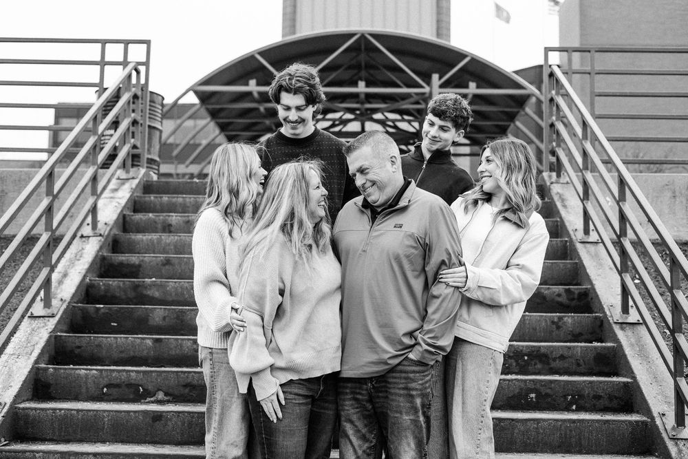 A group of people pose together on concrete steps outside a building in black and white.