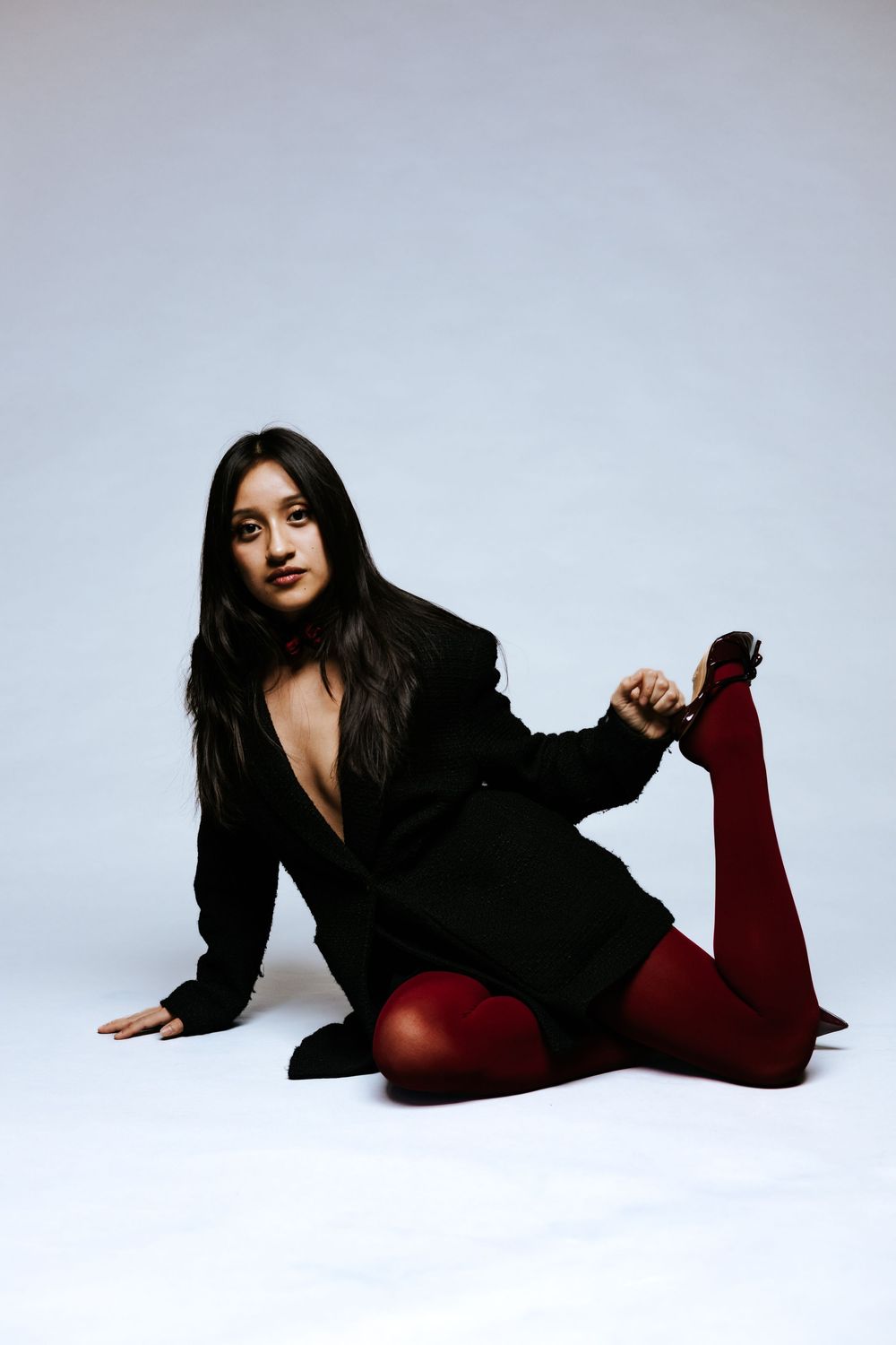 Fashion model in black outfit posing dramatically on white background.