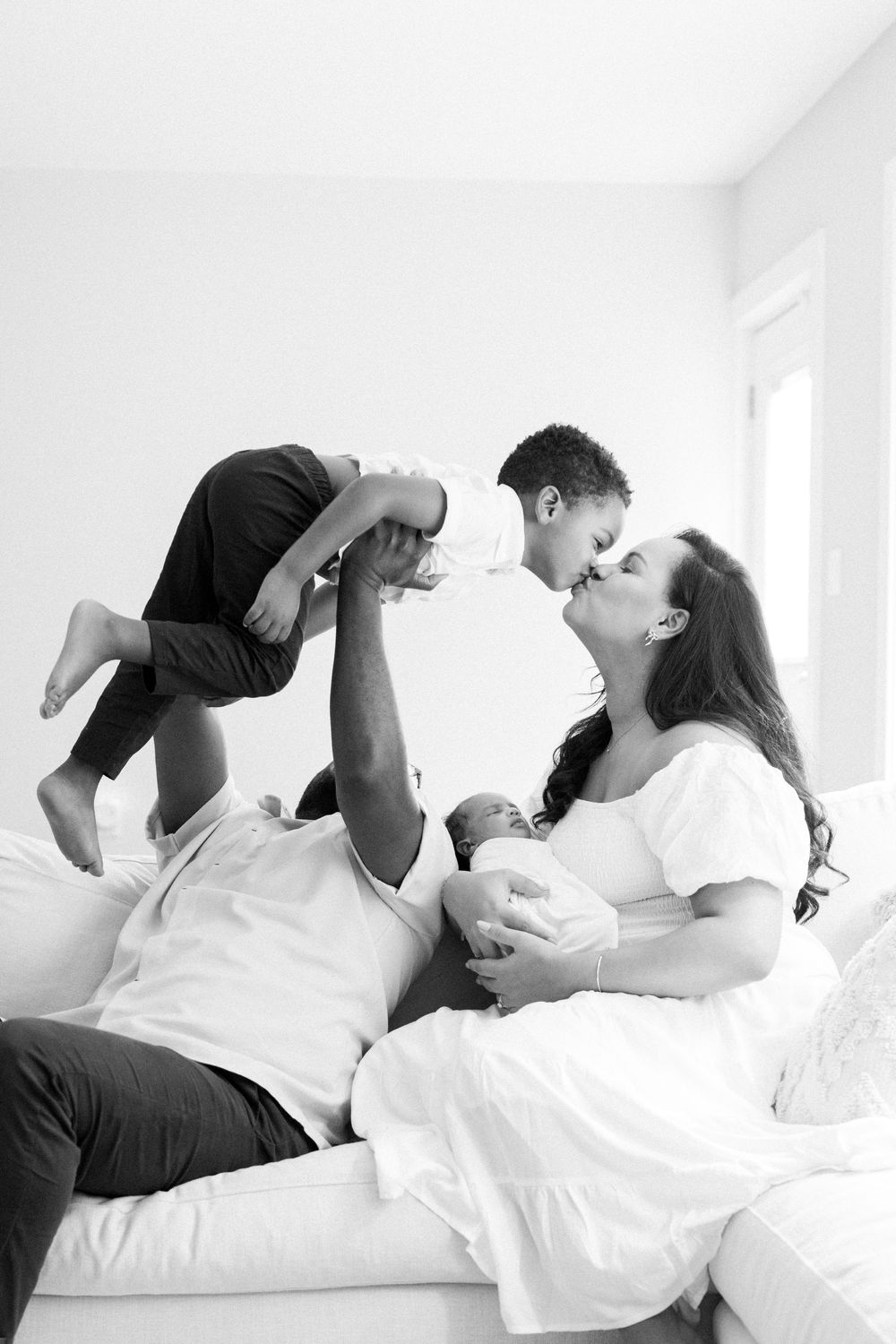 A black and white photo series showing a couple playfully interacting while lounging on a white bed.