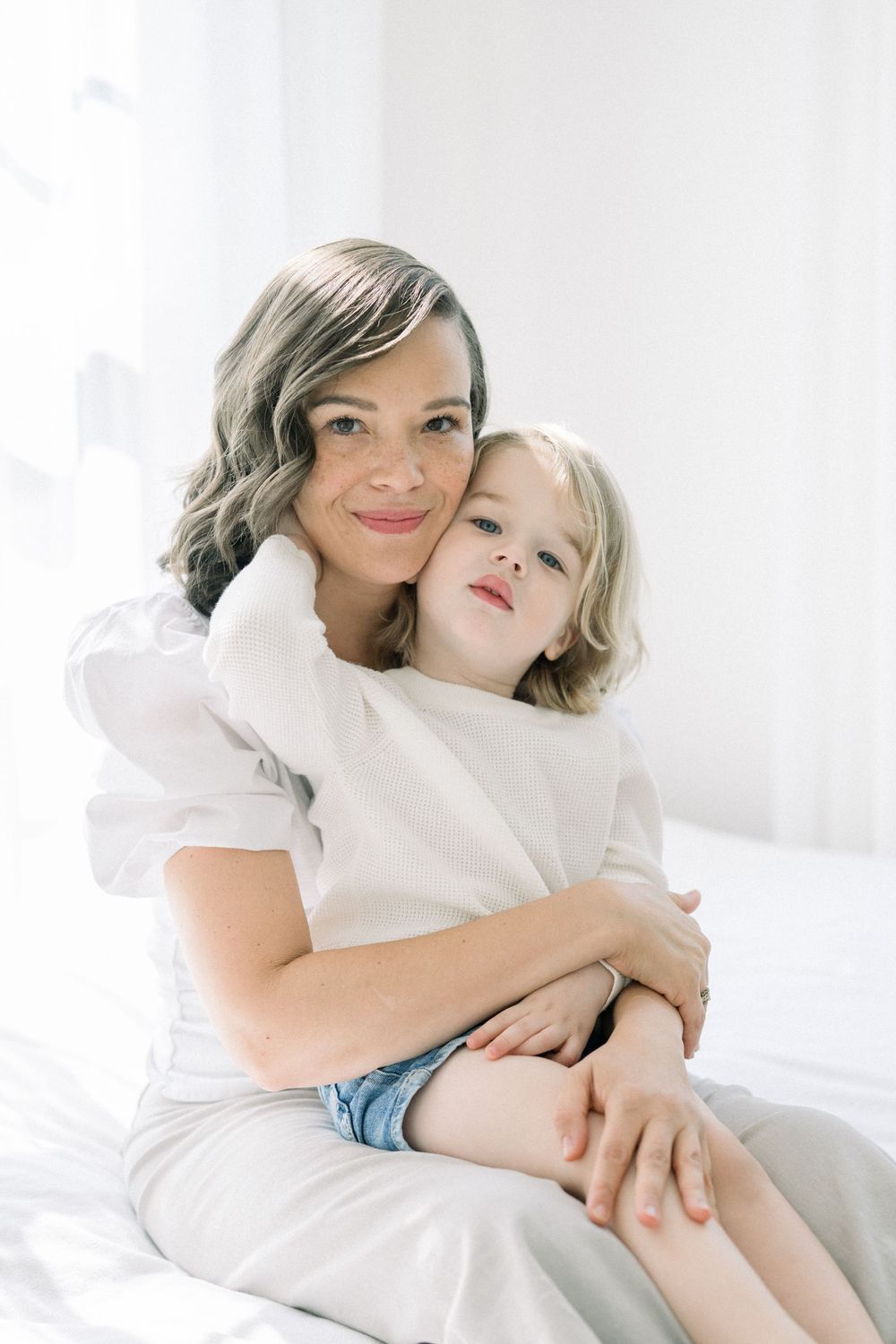A parent and child share tender moments in white clothing against a bright background, captured in a series of photos.