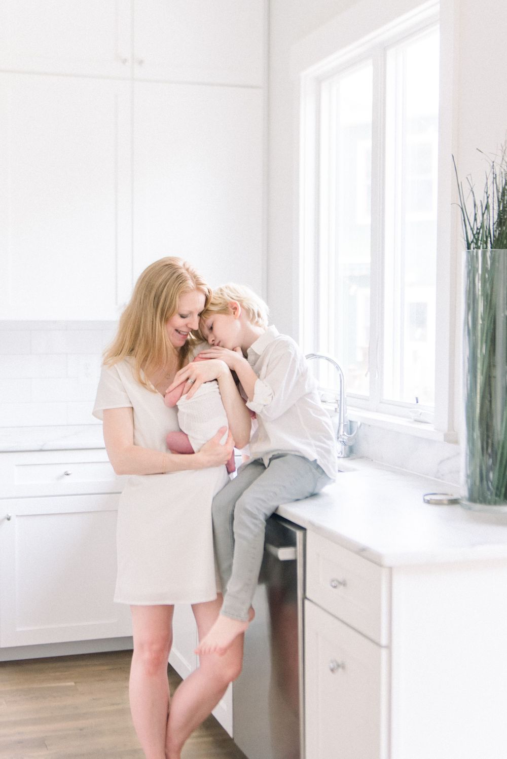 A series of tender moments between a parent and child in a bright white modern room with hardwood floors.
