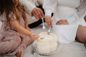 White frosted cake being enjoyed during a beach picnic celebration.