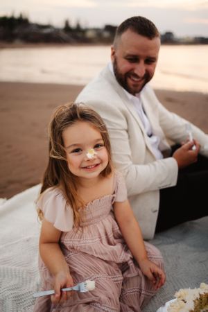 A joyful moment captured on a blanket at sunset showing playful expressions and laughter.