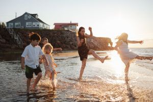 Family playing and splashing in the ocean waves during golden hour at the beach.