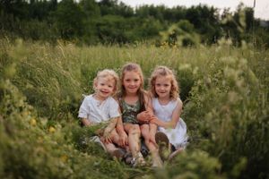Family enjoying a playful moment together in a sunny wildflower meadow.