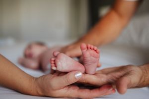 Close up of tiny newborn baby feet being held in gentle hands.