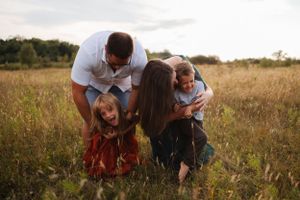 Natural candid moments of family interaction in a golden field during sunset.