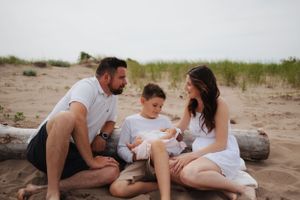 Relaxed beach scene with family gathered on sandy shore near driftwood.