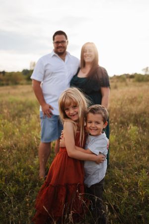 A joyful moment captured in a golden field during sunset with a burgundy dress and white shirt.