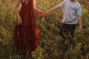 Children playing together in a field at golden hour with warm autumn lighting.