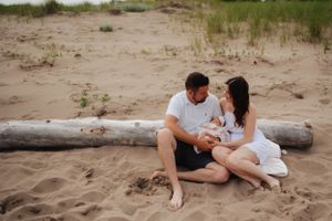 Intimate family gathering on beach with driftwood and natural coastal elements.