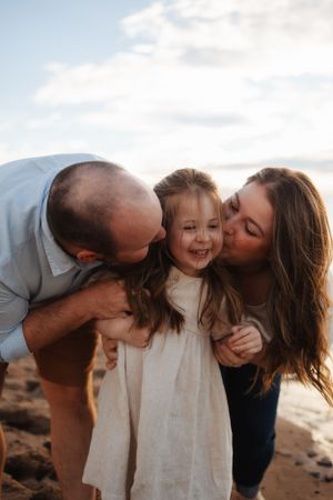 Intimate family moment captured on beach during golden hour.