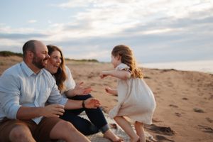 Family sharing playful moment together on sandy beach at sunset.