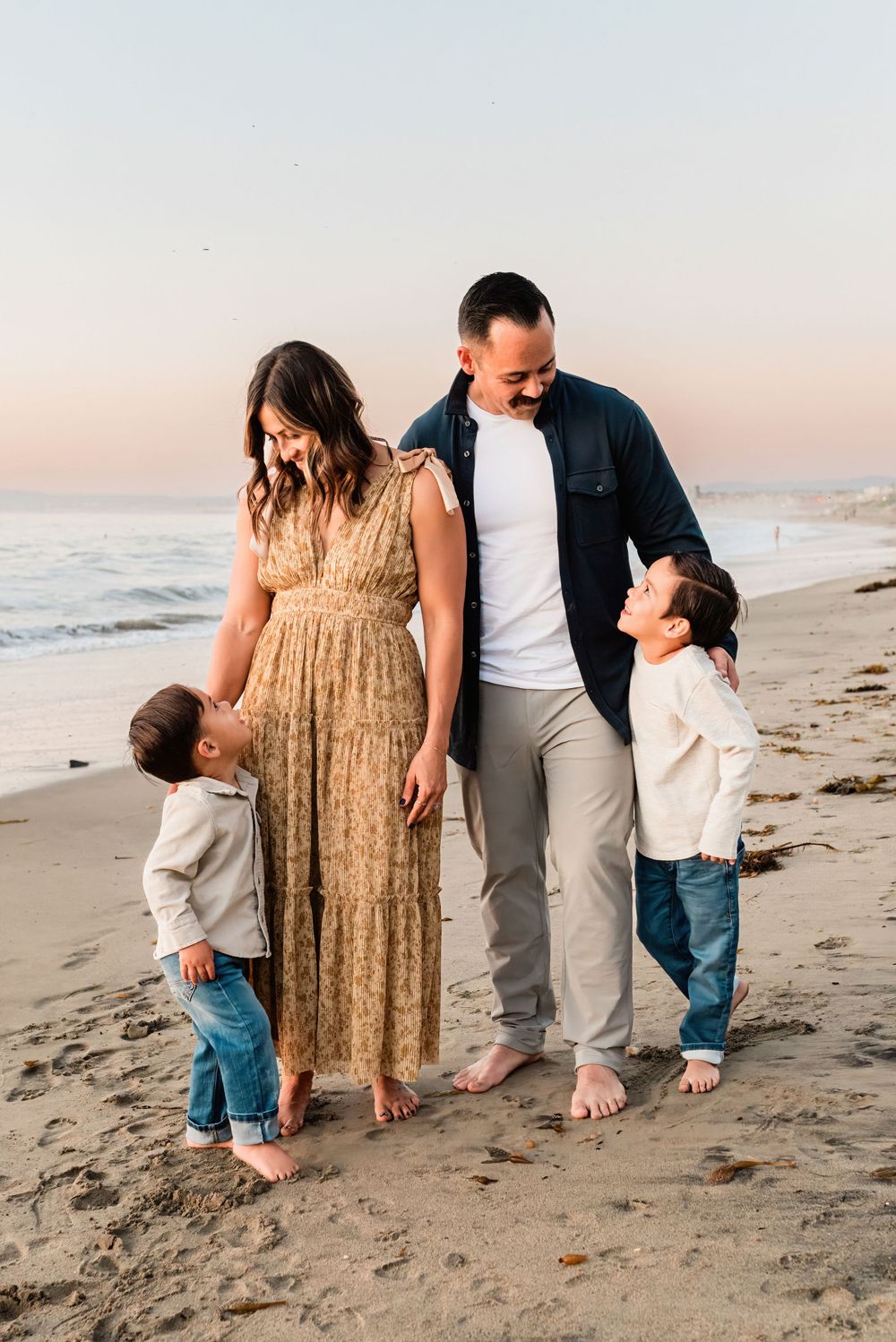 Family looking at each other standing on the beach at sunset in Palos Verdes Estates, California
