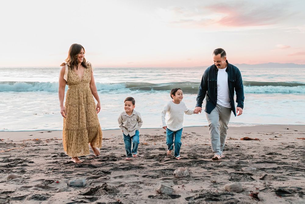 Family of four holding hands on the beach at sunset in Palos Verdes, California