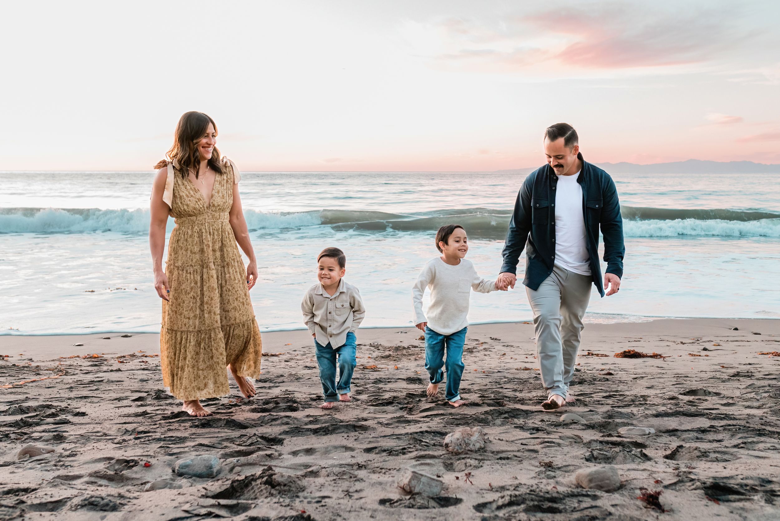 Family of four holding hands on the beach at sunset in Palos Verdes, California
