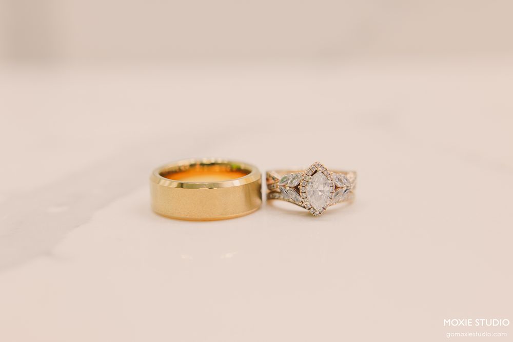 Gold wedding band and diamond engagement ring with ornate silver setting displayed on white surface.