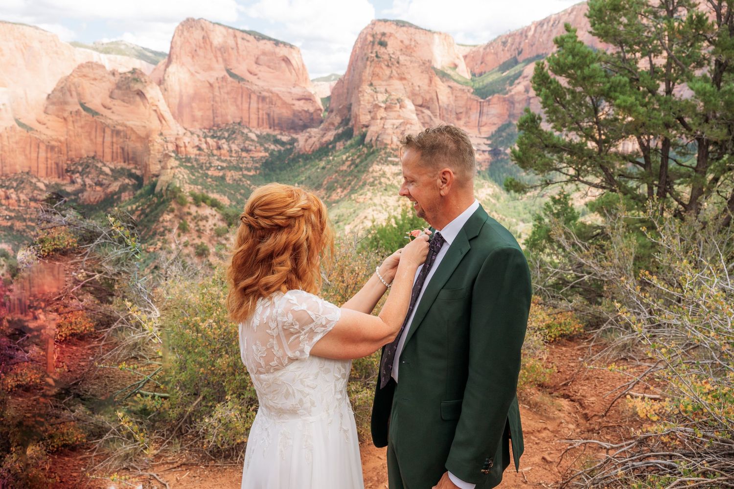 Couple in wedding attire poses at Zion National Park with red rock canyon formations in the background.