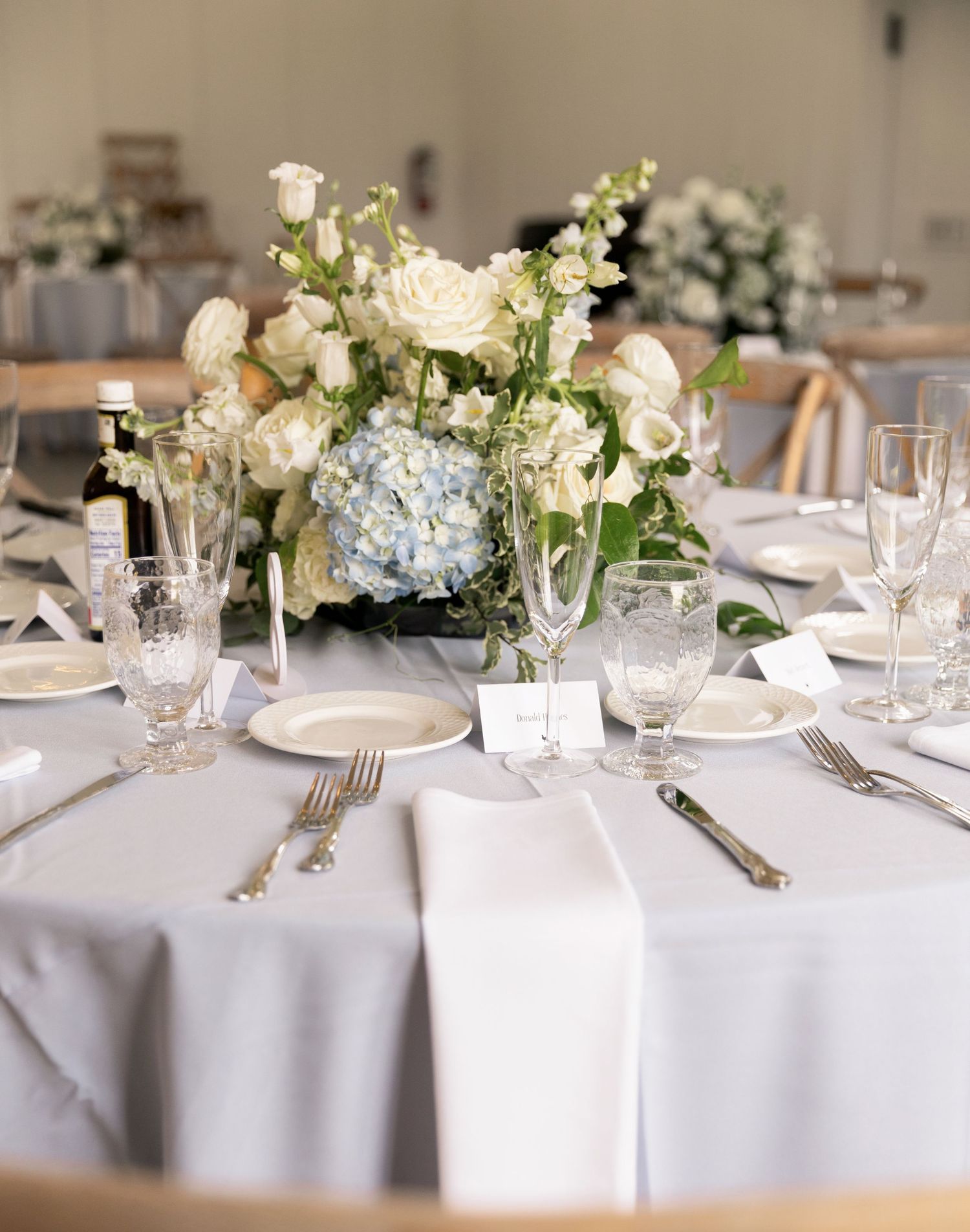Bride and groom share their first dance in an elegant white reception hall with string lights and seated guests.