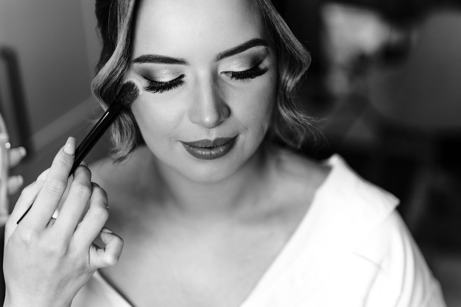Black and white close-up of a bride having her makeup done on the wedding morning
