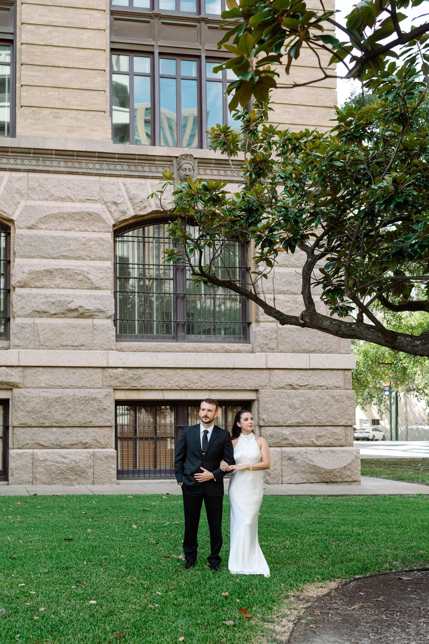 Bride and groom posed on a green space in downtown Houston.