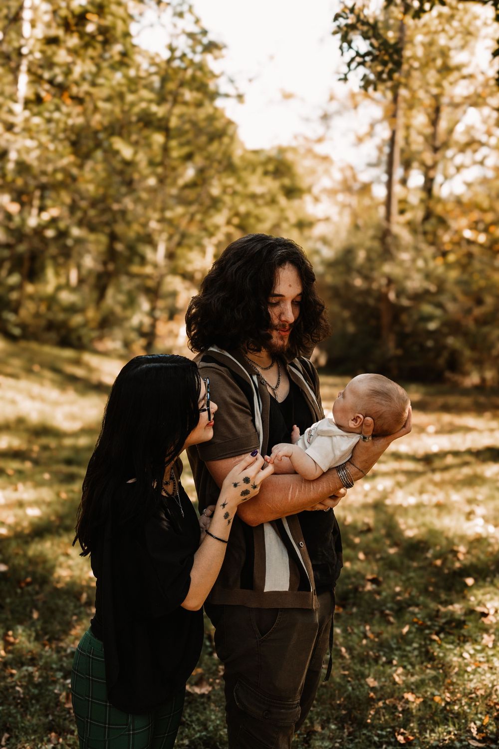 Couple with dark hair gently cradling a newborn baby during a lifestyle family photography session in Oak Ridge, Tennessee.