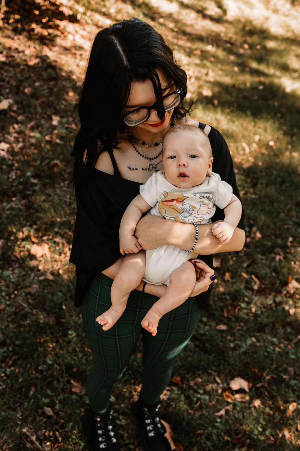 Woman with dark hair and glasses holds a smiling baby during a lifestyle family photography session in Oak Ridge, Tennessee.