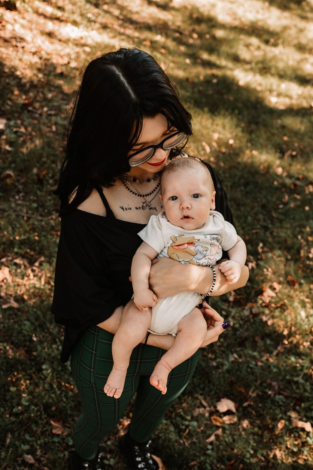 Woman with dark hair and glasses holds her baby during a lifestyle family photography session in Oak Ridge, Tennessee.