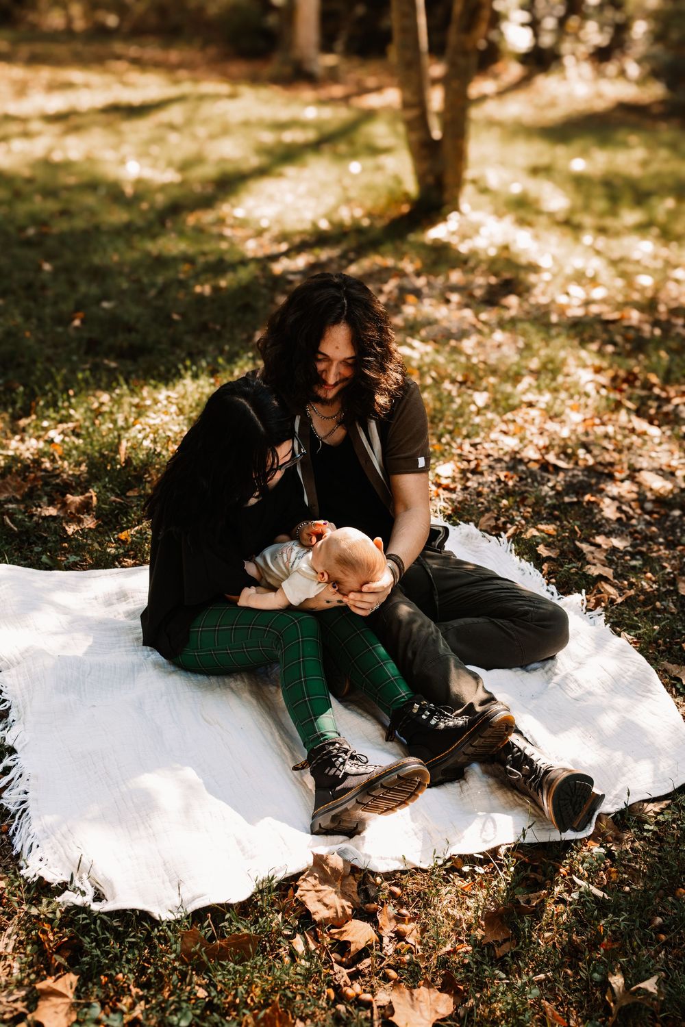 Family holding a baby surrounded by autumn leaves and trees during a lifestyle family photography session in Oak Ridge, Tennessee.