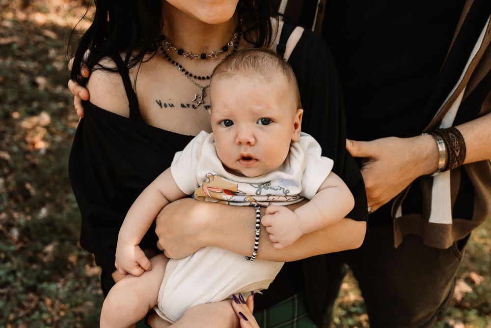 Baby boy is held by a tattooed parent in black during a lifestyle family photography session in Oak Ridge, Tennessee.